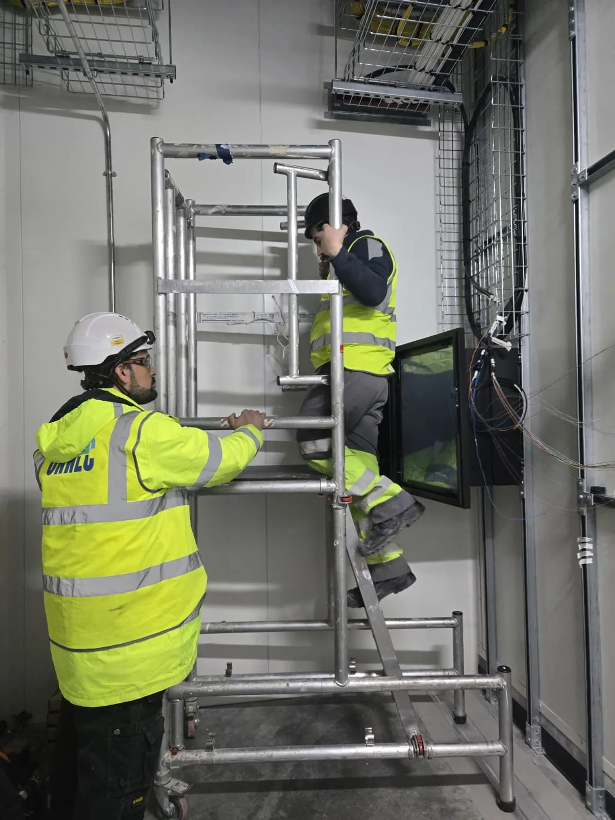 Carded engineers installing network cabling from mobile access tower
